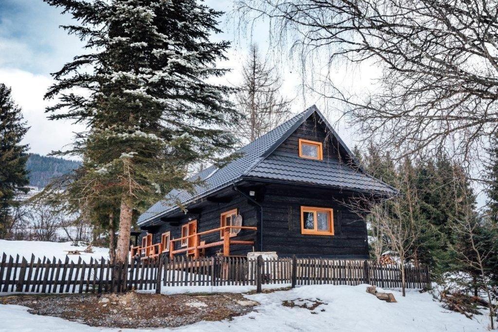 una cabaña de madera en la nieve con una valla en chalupa matko a kubko en Bravačov