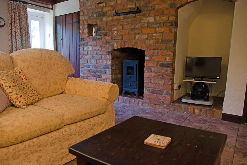 a living room with a couch and a brick fireplace at 2 Hope Cottage in Spilsby