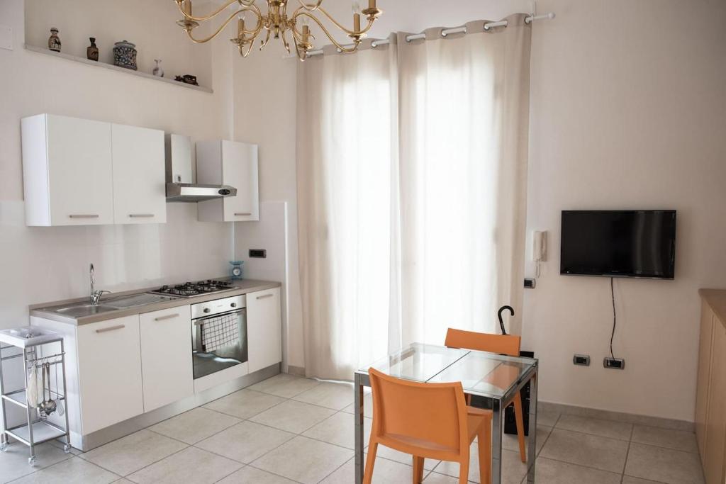 una cocina con armarios blancos y una mesa con sillas. en Central Apartment - Residenza Battistessa en Caserta