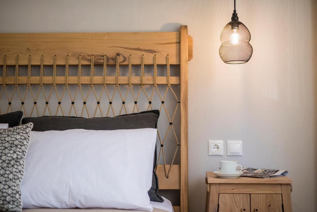 1 dormitorio con 1 cama con cabecero de madera y lámpara en Anemelia Luxury Apartments en Argostoli