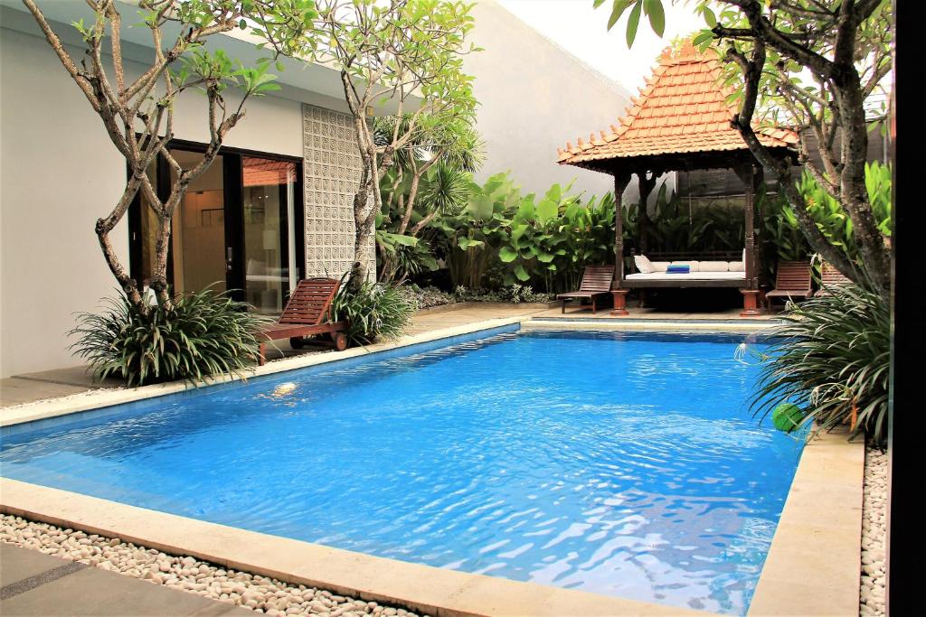 una gran piscina azul frente a una casa en The Nibbana Villas, en Seminyak