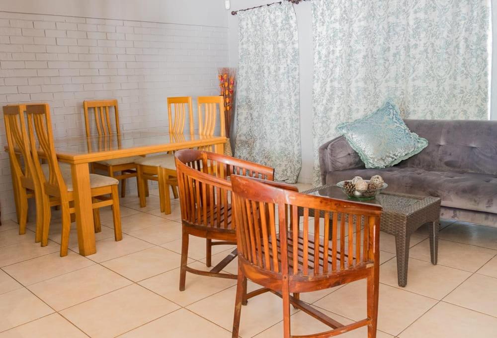 sala de estar con mesa, sillas y sofá en Cape Pine Guest House, en Kuilsrivier