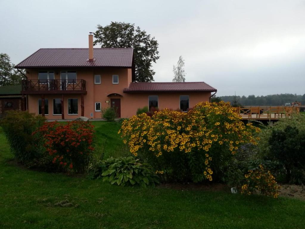 a house on a hill with flowers in front of it at "Lībieši" in Purmsāti