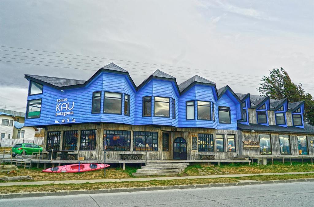 a blue house with a surfboard in front of it at Kau Lodge in Puerto Natales