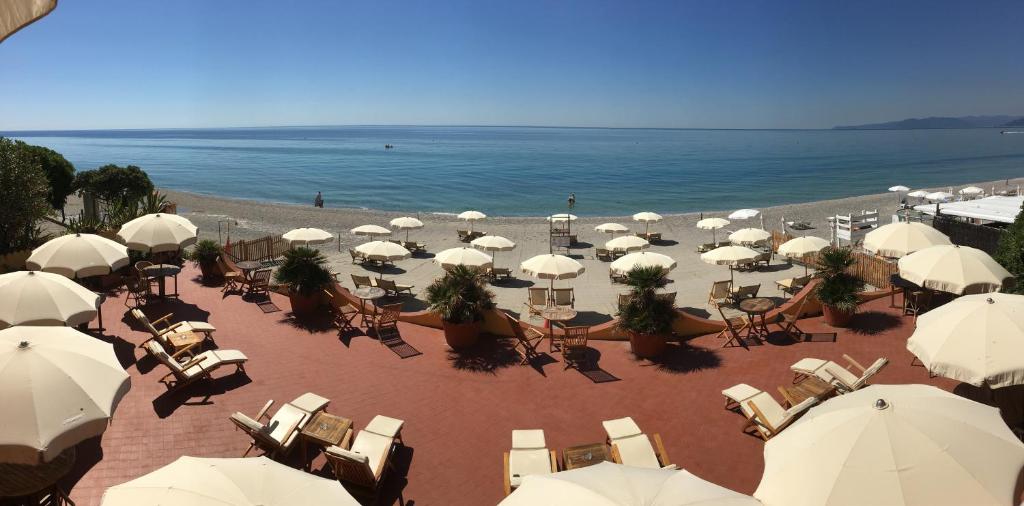 uma praia com guarda-sóis e cadeiras brancas e o oceano em Miramare di Varigotti em Varigotti