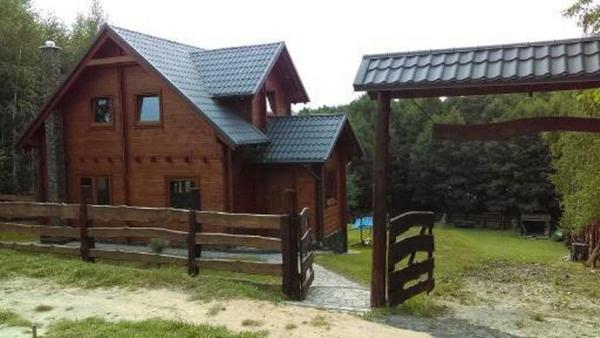 a wooden cabin with a fence and a gazebo at Domek u Charnasia in Biskupiec