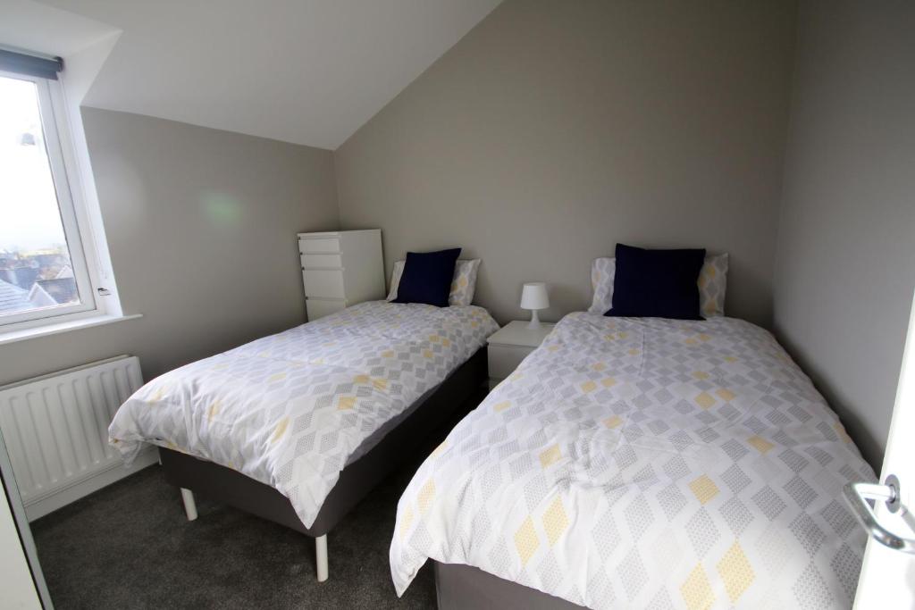 a bedroom with two beds and a window at Strand House 2 in Portstewart