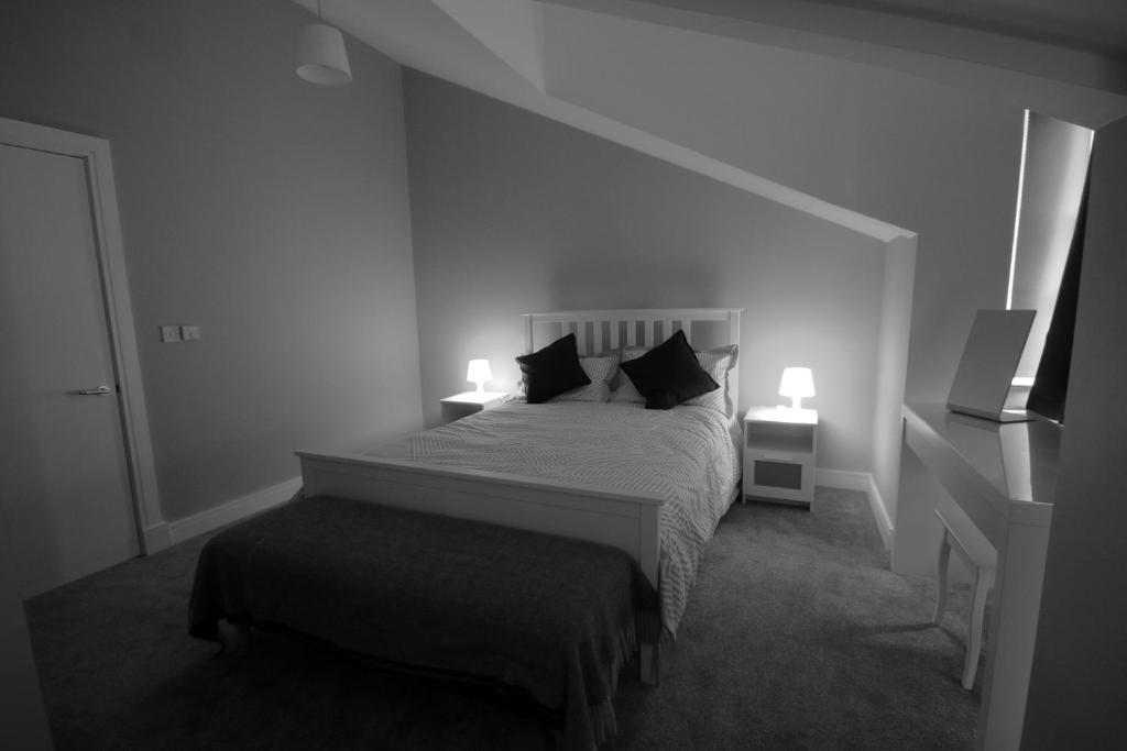 a bedroom with a bed with two lamps and a ottoman at Strand House 2 in Portstewart