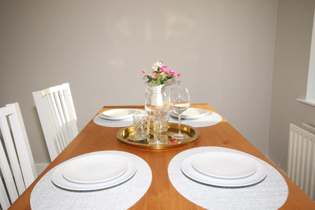 a dining room table with white plates and wine glasses at Strand House 2 in Portstewart