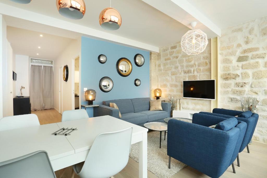 - un salon avec une table blanche et des chaises bleues dans l'établissement Residence Tour Eiffel by Studio prestige, à Paris