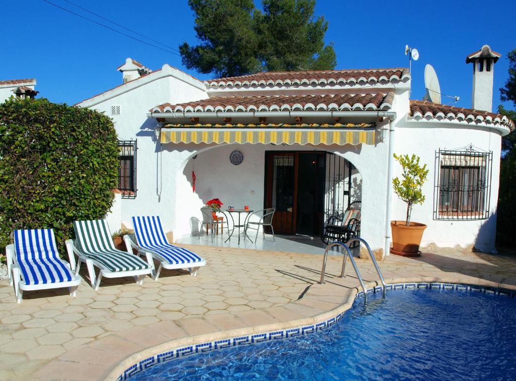 a swimming pool with two chairs and a house at Las Bellotas in Moraira