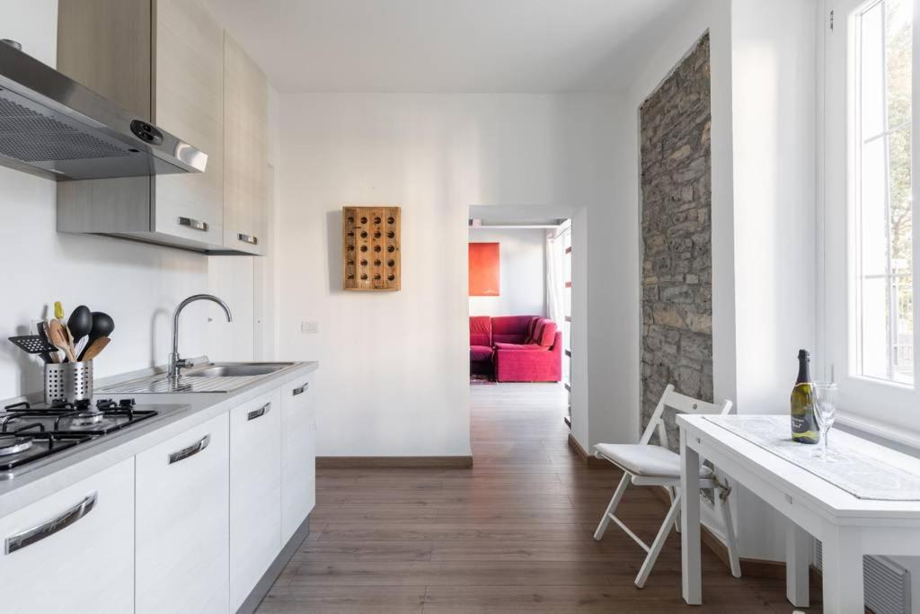 a kitchen with white cabinets and a table and a red couch at Tata's Home in Cernobbio