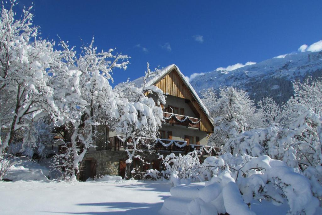 a house covered in snow next to a forest of trees at Chalet Solneige in Vaujany