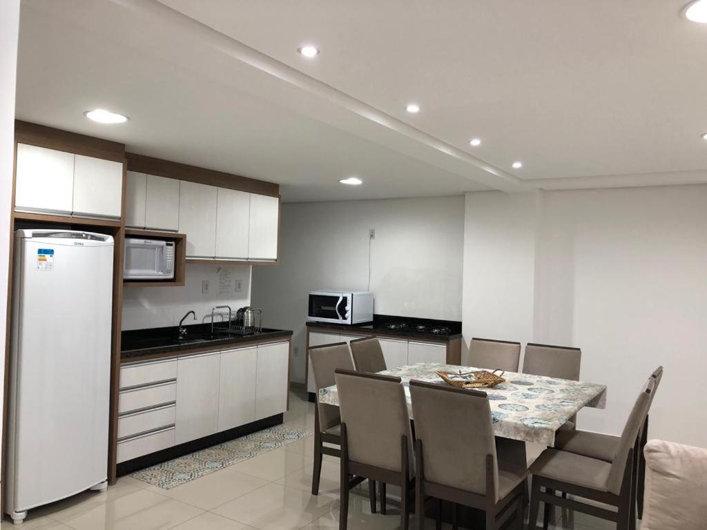 a kitchen with a table with chairs and a refrigerator at Apartamento Ed. London in Piratuba