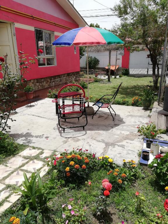 un patio con mesa, sombrilla y flores en Wayrashaus, en Cochabamba