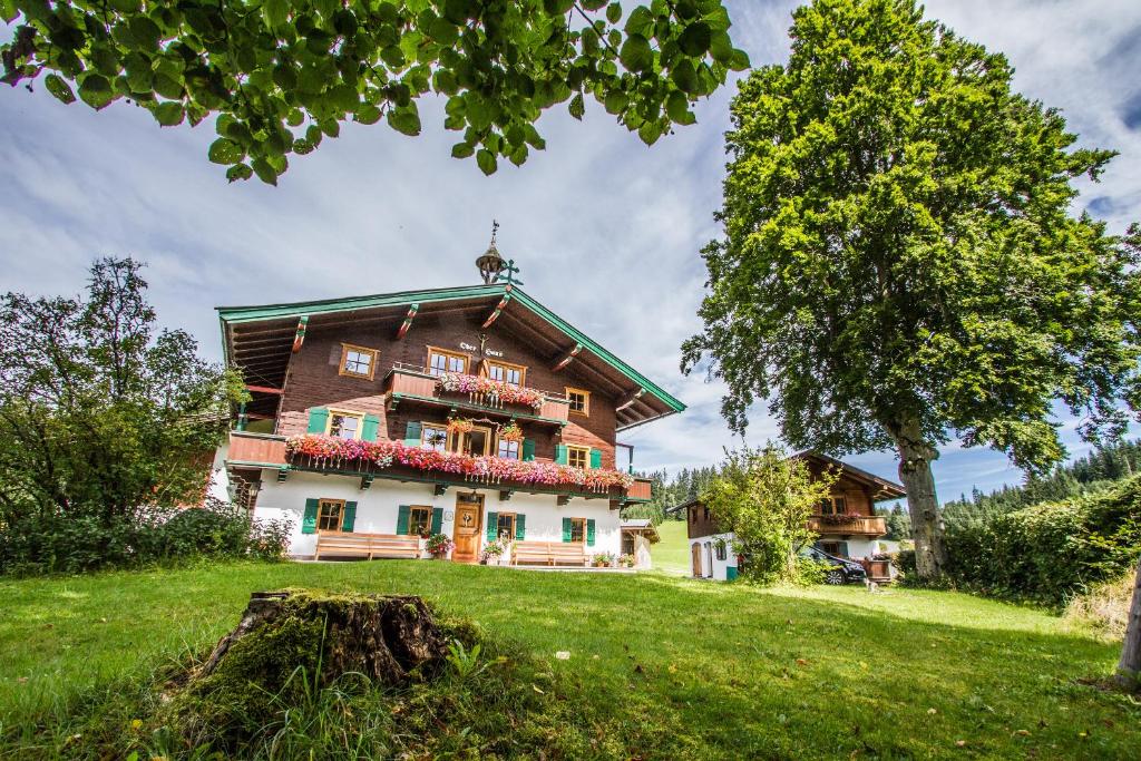 ein großes Haus auf einem Hügel mit einem Baum in der Unterkunft Hof Oberhaus in Kitzbühel