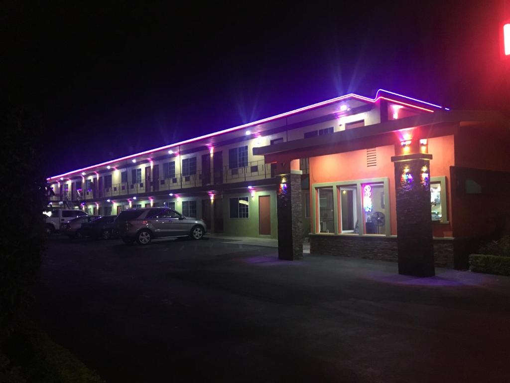 um edifício com carros estacionados num parque de estacionamento à noite em Villa Park Motel em Orange