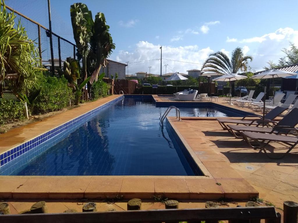 a swimming pool with chairs and umbrellas at Itacimirim - Quinta das Lagoas Residence in Itacimirim