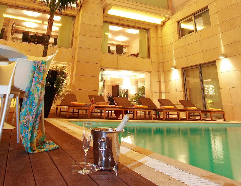 un hotel con piscina y una bebida en una mesa en Nafs Hotel, en Nafpaktos