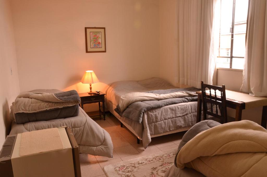 a bedroom with two beds and a table and a window at Hotel Maristela in São Joaquim