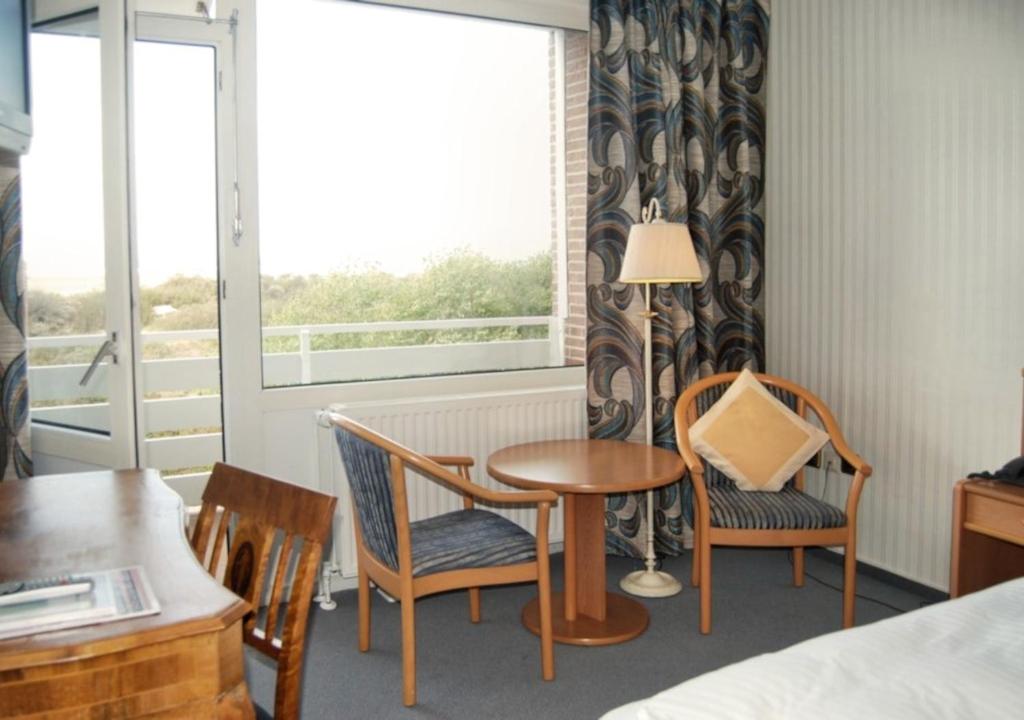 une chambre avec une table, des chaises et une fenêtre dans l'établissement Hotel das Miramar, à Borkum