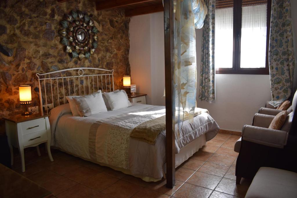 Un dormitorio con una cama y una silla y una ventana. en Hostal Rural Molino Del Bombo, en Aracena