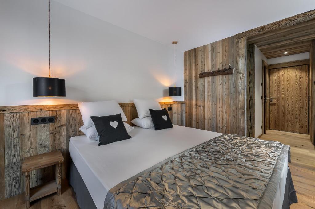 a bedroom with a large white bed and wooden walls at Chalet Chez Sylvain in Le Fornet