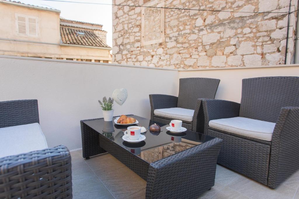 un patio con sillas y una mesa con tazas. en Aurum Apartment, en Šibenik