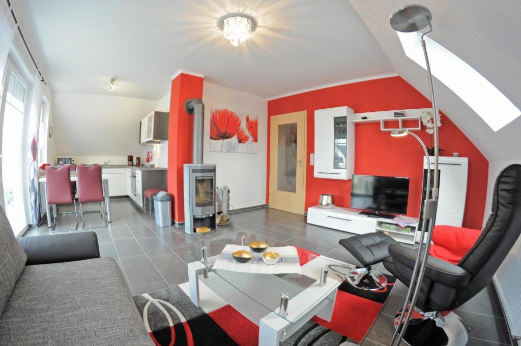 ein Wohnzimmer mit einer Wand mit roten Akzenten in der Unterkunft Ferienhaus Müritzidyll / OG-Appartement in Marienfelde