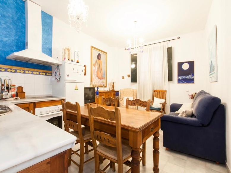cocina y sala de estar con mesa de madera y sillas en Apartamento Santa Cruz, en Sevilla