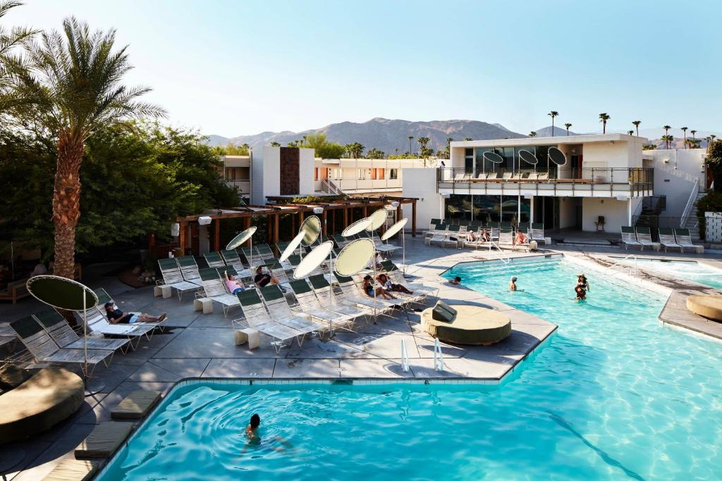 a pool with chairs and people in a resort at Ace Hotel and Swim Club Palm Springs in Palm Springs