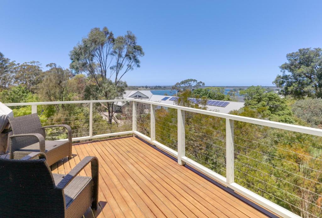 a balcony with a wooden deck with chairs and trees at Foreshore - Spacious Metung Escape in Metung