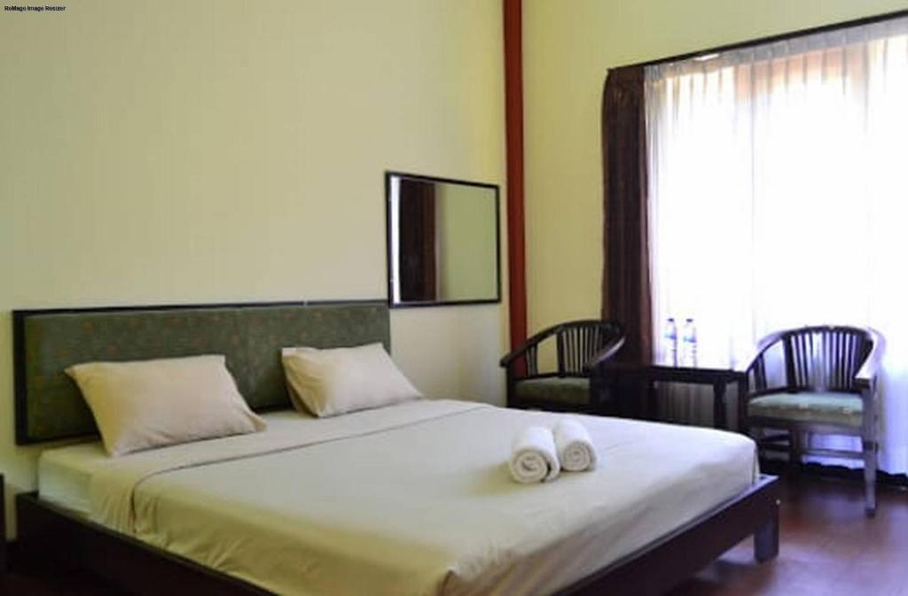 a bedroom with a large bed with two towels on it at Hotel Tiger in Yogyakarta