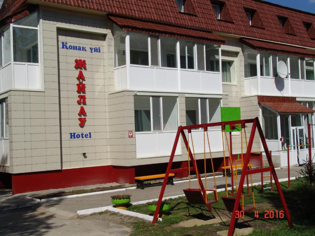 un edificio con parco giochi di fronte di Zhaylau Hotel a Shchuchinsk