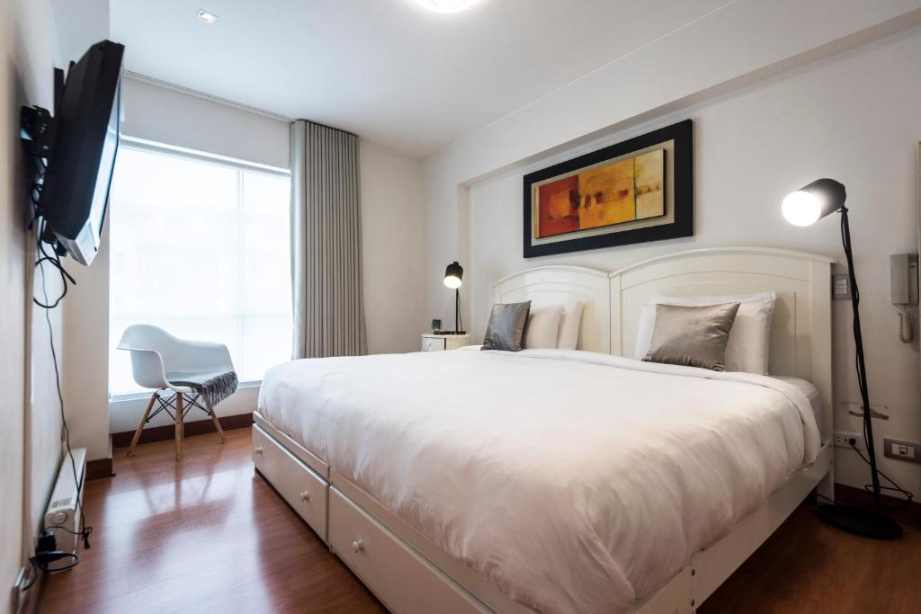 Un dormitorio con una gran cama blanca y una ventana en InkaHuset Miraflores Deluxe, en Lima