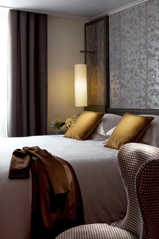 a bedroom with a large bed and a chair at Hotel America in Cannes