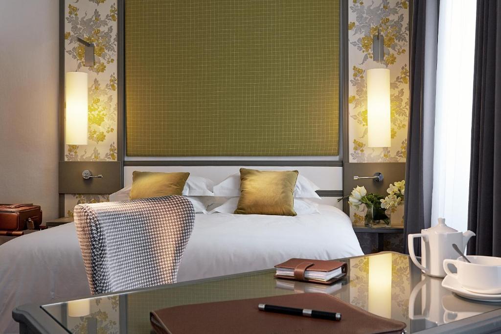 una camera d'albergo con letto e scrivania con tavolo in vetro di Hotel America a Cannes