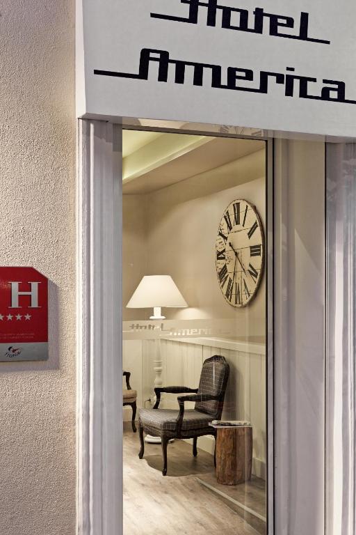 a lobby with a clock and a chair in a room at Hotel America in Cannes