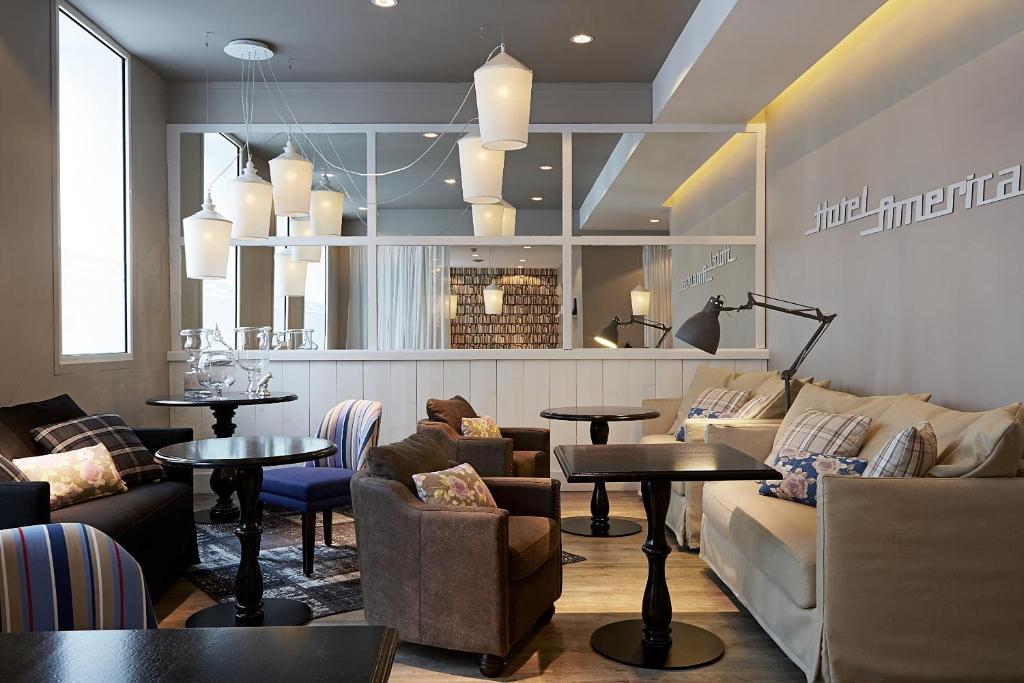 a restaurant with couches and tables in a room at Hotel America in Cannes