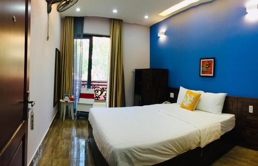 SPRING HOTEL في Thu Dau Mot: غرفة نوم بسرير كبير بجدار ازرق