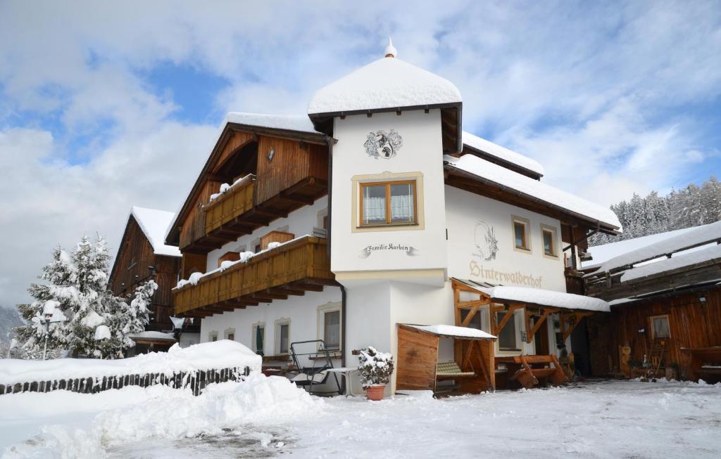 un edificio cubierto de nieve con nieve en el suelo en Zimmer - Hinterwalderhof, en Rio di Pusteria