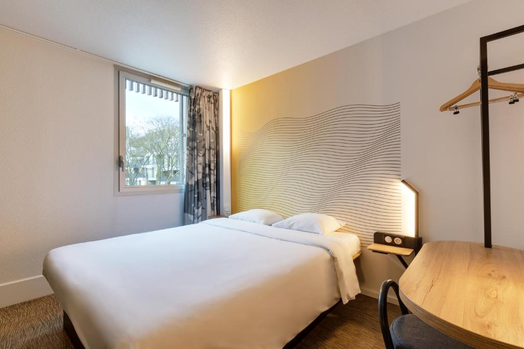 a bedroom with a large white bed and a table at B&B HOTEL Lille Centre Grand Palais in Lille