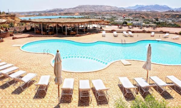 a beach area with chairs, tables and umbrellas at Aida Hotel Sharm El Sheikh in Sharm El Sheikh