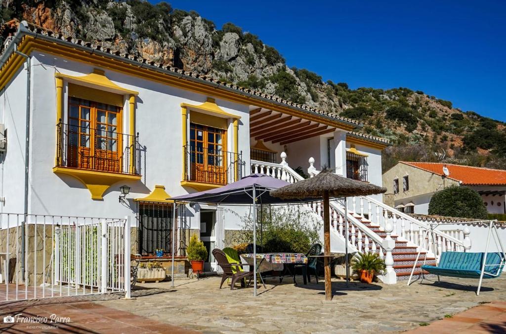 a white house with a table and an umbrella at Villa Cristina in Benaoján