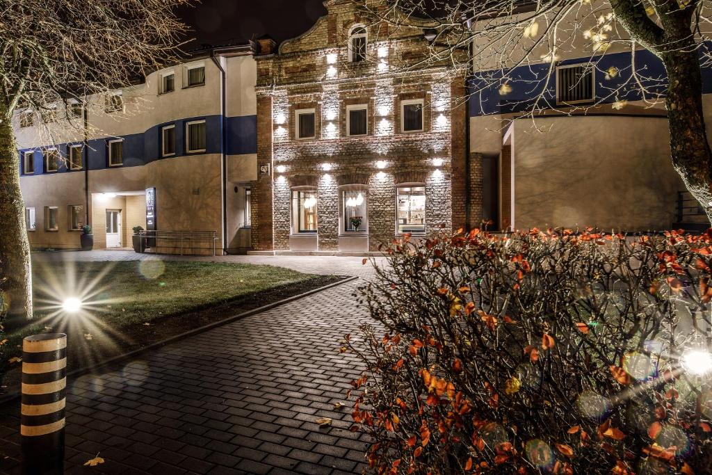 un vieux bâtiment avec des lumières allumées la nuit dans l'établissement Hotel Tomas, à Šiauliai
