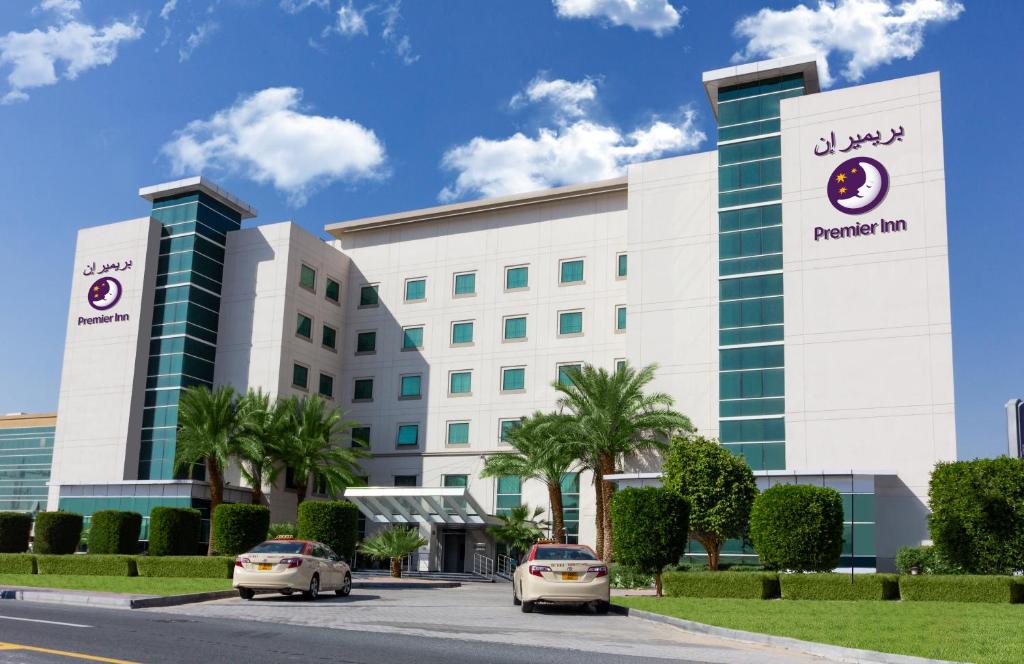 dos coches estacionados frente a un hotel en Premier Inn Dubai Investments Park, en Dubái