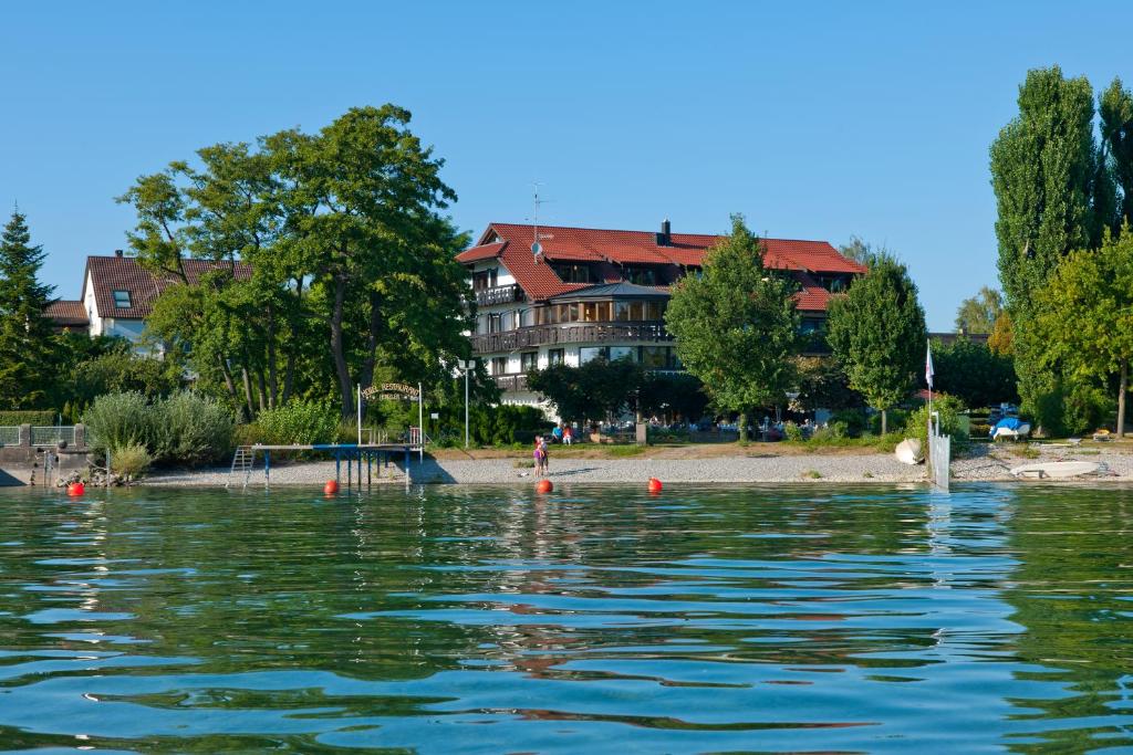 Blick auf ein Haus vom Wasser in der Unterkunft Hotel Heinzler am See in Immenstaad am Bodensee