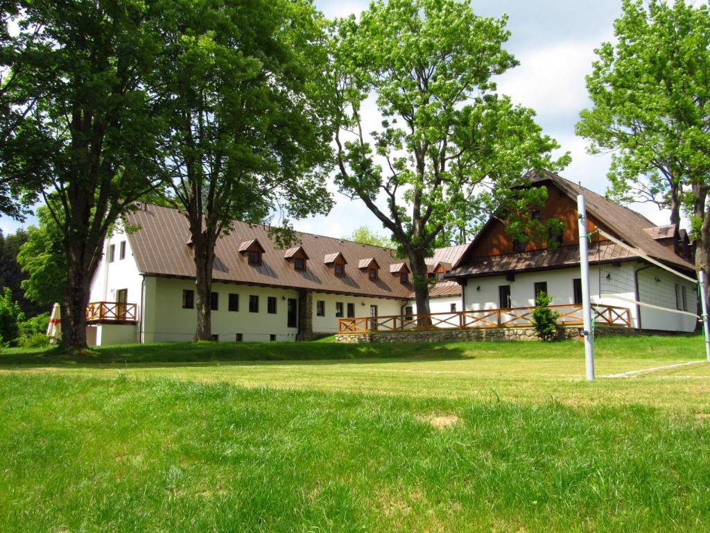 a white house with a gambrel roof at Rodinný hotel Pod Bílou skálou in České Křižánky