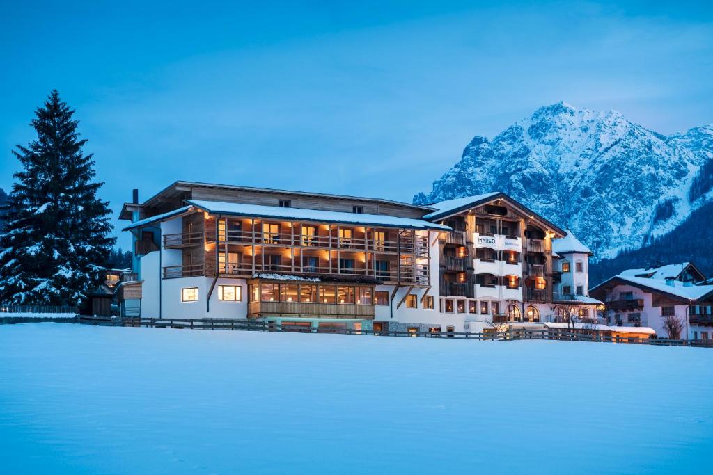 a large building with snow in front of a mountain at Hotel Mareo Dolomites in San Vigilio Di Marebbe