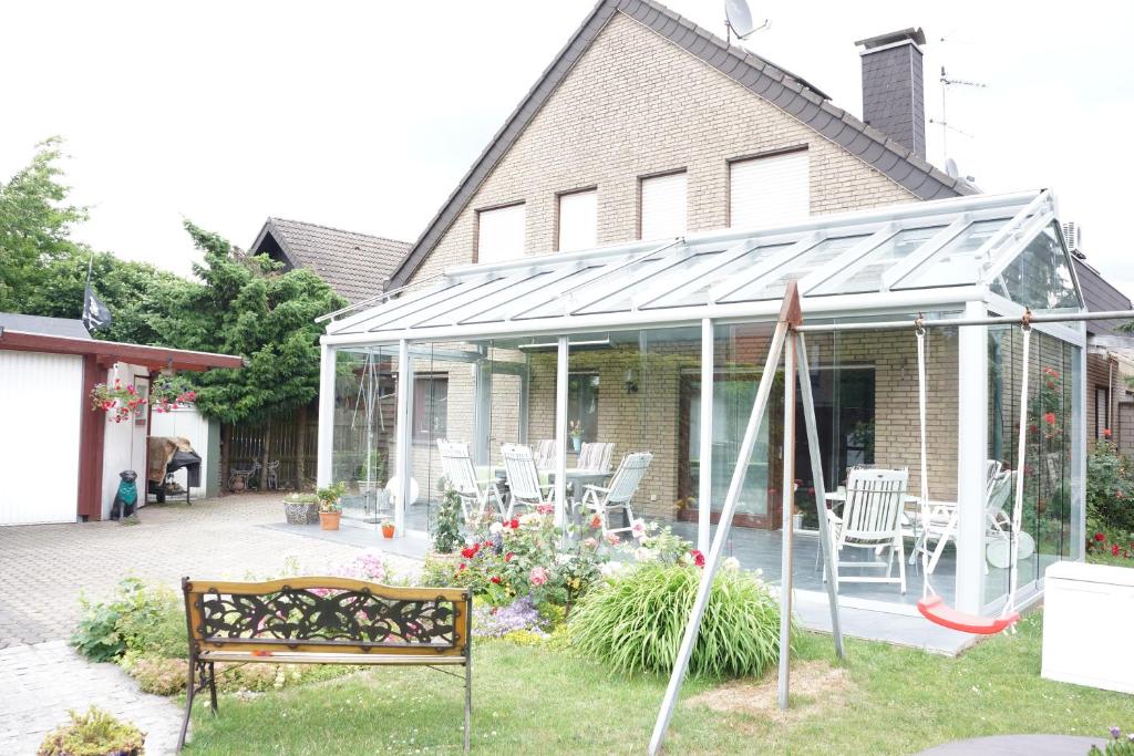 Casa con salón acristalado con sillas y banco en Apartmentvermietung Meerbusch, en Meerbusch